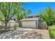 Two-story home with a two-car garage, a long driveway, fenced yard, and mature trees at 8032 Lee Ct, Arvada, CO 80005