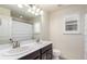 Bright bathroom featuring double sinks, a dark wood vanity, and a large mirror at 690 W 172Nd Pl, Broomfield, CO 80023