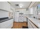 Charming kitchen featuring white cabinets, appliances, wood countertop trim, and vinyl flooring at 1299 S Dale Ct, Denver, CO 80219