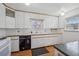Classic kitchen with white cabinets, vintage appliances, wood countertop trim, and a view from two windows at 1299 S Dale Ct, Denver, CO 80219