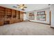 Inviting living room showcasing built-in wooden shelving, plush carpet, and two bright windows at 1299 S Dale Ct, Denver, CO 80219