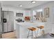 Bright kitchen featuring white cabinets, stainless steel appliances, and a stylish breakfast bar with modern stools at 9658 W Chatfield Ave # D, Littleton, CO 80128