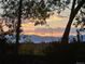 Stunning sunset view over the mountains, framed by silhouetted trees and shrubbery at 9025 Jellison Ct, Broomfield, CO 80021