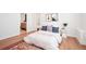 Bright bedroom with light hardwood floors, area rug, and a peek into the ensuite bathroom at 5787 Powell Rd, Parker, CO 80134