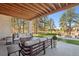 Spacious covered patio featuring comfortable seating, stone accents, and an open view of the expansive, tree-lined backyard at 5787 Powell Rd, Parker, CO 80134