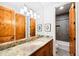 Bathroom featuring wood cabinets, granite countertop, large mirror, and walk-in shower at 4491 Shoshone Dr, Larkspur, CO 80118