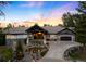 Stunning stone home with a covered entrance, lush landscaping, and a circular driveway at sunset at 4491 Shoshone Dr, Larkspur, CO 80118