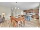 Open floor plan featuring a dining table with wood chairs, stainless appliances in the kitchen, and wood laminate flooring at 7888 E 139Th Pl, Brighton, CO 80602