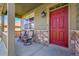Inviting front porch with covered seating area, red door and stone accents for a touch of elegance and charm at 7888 E 139Th Pl, Brighton, CO 80602