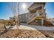 Backyard view showcasing a raised deck with stairs, a patio, and a young tree in the yard at 1087 E Hopkins Dr, Elizabeth, CO 80107