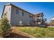Backyard showcasing the home's gray exterior, a walkout deck, green grass, and landscaped flowerbeds at 1087 E Hopkins Dr, Elizabeth, CO 80107