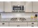 Close-up of stainless steel microwave and gas stovetop featuring a granite countertop at 2932 Eagle Wing Way, Castle Rock, CO 80109