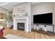 Living room featuring a fireplace with white mantel, hardwood floors and a large TV at 2932 Eagle Wing Way, Castle Rock, CO 80109