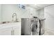 Modern laundry room featuring a stainless steel sink, modern washer and dryer, and sleek white cabinets at 6439 E Maplewood Ave, Centennial, CO 80111
