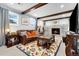 Inviting living room with exposed wood beams, stone fireplace, comfortable leather sofa, and colorful area rug at 6439 E Maplewood Ave, Centennial, CO 80111