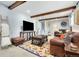 Spacious living room featuring a leather sofa, decorative area rug, exposed beams, and a staircase in the background at 6439 E Maplewood Ave, Centennial, CO 80111