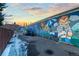 Street art mural decorates a building wall under a vibrant sunset with parked cars nearby creates a lively neighborhood scene at 1235 31St St, Denver, CO 80205