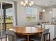 Sunlit dining room featuring a large round wooden table, modern chairs, and a view of the backyard at 8346 E 132Nd Dr, Thornton, CO 80602