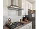 Close up on kitchen with stainless steel range hood, gray cabinets, and tiled backsplash at 8346 E 132Nd Dr, Thornton, CO 80602