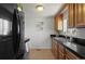 This compact kitchen is furnished with black appliances, wood cabinets, and tile floors at 3300 Oneida St, Denver, CO 80207