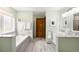 Bright bathroom featuring a soaking tub, neutral tile, and wood door at 3257 Sun Ridge Ln, Evergreen, CO 80439