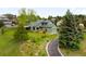 Charming green home with a well-manicured lawn, complemented by mature trees and a curved driveway at 3257 Sun Ridge Ln, Evergreen, CO 80439