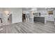 Open floor plan with gray wood floors leading into a white kitchen with stainless appliances at 5419 E 113Th Ave, Thornton, CO 80233