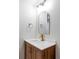 Small bathroom with wood vanity, white countertop, and arched mirror at 7154 S Hudson Cir, Centennial, CO 80122