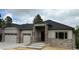 Beautiful single-story home showcasing stone pillars, gray siding, and a three-car garage at 6152 Powell Rd, Parker, CO 80134