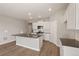Bright kitchen features white cabinets, stainless appliances, island with sink, and wood-look floors at 18336 Prince Hill Cir, Parker, CO 80134