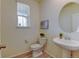 Cozy powder room features a pedestal sink, round mirror, wood-look floors, and natural light from the window at 5686 Eagle River Pl, Brighton, CO 80601