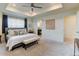 Bright primary bedroom featuring tray ceiling and adjacent bathroom at 5686 Eagle River Pl, Brighton, CO 80601