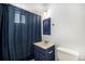 Bathroom with blue accents featuring a shower with blue curtain, vanity, mirror, and toilet at 10555 Montview Blvd, Aurora, CO 80010