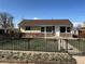 Charming single-story home with a stone facade and a well-manicured lawn with black metal fence at 10555 Montview Blvd, Aurora, CO 80010