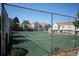 Tennis court surrounded by a chain-link fence, with townhouses and mature trees in the background at 1128 S Ventura Cir # K, Aurora, CO 80017