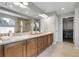 Well-lit bathroom with dual sinks, a large mirror, wooden cabinets, and a glass-enclosed shower at 2354 Cactus Bloom Ct, Castle Rock, CO 80109