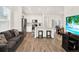 Open-concept living room with modern furnishings, light-colored walls, wood floors, and seamless flow to kitchen and dining at 470 Kiowa Ave, Bennett, CO 80102