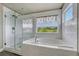Modern bathroom featuring a glass shower, soaking tub, white subway tile, and a view through the window at 3434 Fantasy Pl, Castle Rock, CO 80109