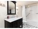 Renovated bathroom with a black vanity, marble countertop, and classic black-and-white tile flooring at 6 White Alder, Littleton, CO 80127