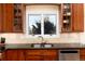 Well-lit kitchen sink with stainless steel faucet, granite countertops, tile backsplash, and cherry wood cabinets at 6 White Alder, Littleton, CO 80127