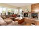 Bright living room with comfortable seating, fireplace with brick surround, and multiple windows for natural light at 6 White Alder, Littleton, CO 80127