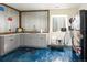 Stylish kitchenette with gray cabinets, stainless steel sink, and vibrant blue epoxy flooring at 1334 Barberry Trl, Elizabeth, CO 80107