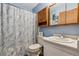 Bright bathroom featuring a vanity, toilet, and shower with marble pattern curtain and blue walls at 1418 5Th St, Fort Lupton, CO 80621