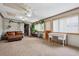 Cozy living room with large windows, brown leather sofa, carpeted floors, and many plants at 1418 5Th St, Fort Lupton, CO 80621