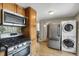 Galley kitchen featuring stainless steel appliances, including a gas range, microwave, and stacked washer/dryer at 2415 Chase St, Edgewater, CO 80214