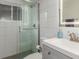 Modern bathroom featuring a sleek glass-enclosed shower, white tile, and a stylish vanity sink at 3841 W Quinn Pl, Denver, CO 80236