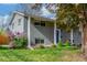 Charming gray brick home featuring a well-manicured lawn, mature trees, and a bright blue front door at 3841 W Quinn Pl, Denver, CO 80236