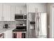 Modern kitchen with white cabinetry, stainless steel appliances, and stylish backsplash at 3841 W Quinn Pl, Denver, CO 80236