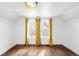 Bedroom featuring three bright windows, yellow curtains, and hardwood floors at 5103 Quitman St, Denver, CO 80212