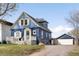 View of a charming two-story blue home with a garage and driveway, showcasing the property's curb appeal at 5103 Quitman St, Denver, CO 80212